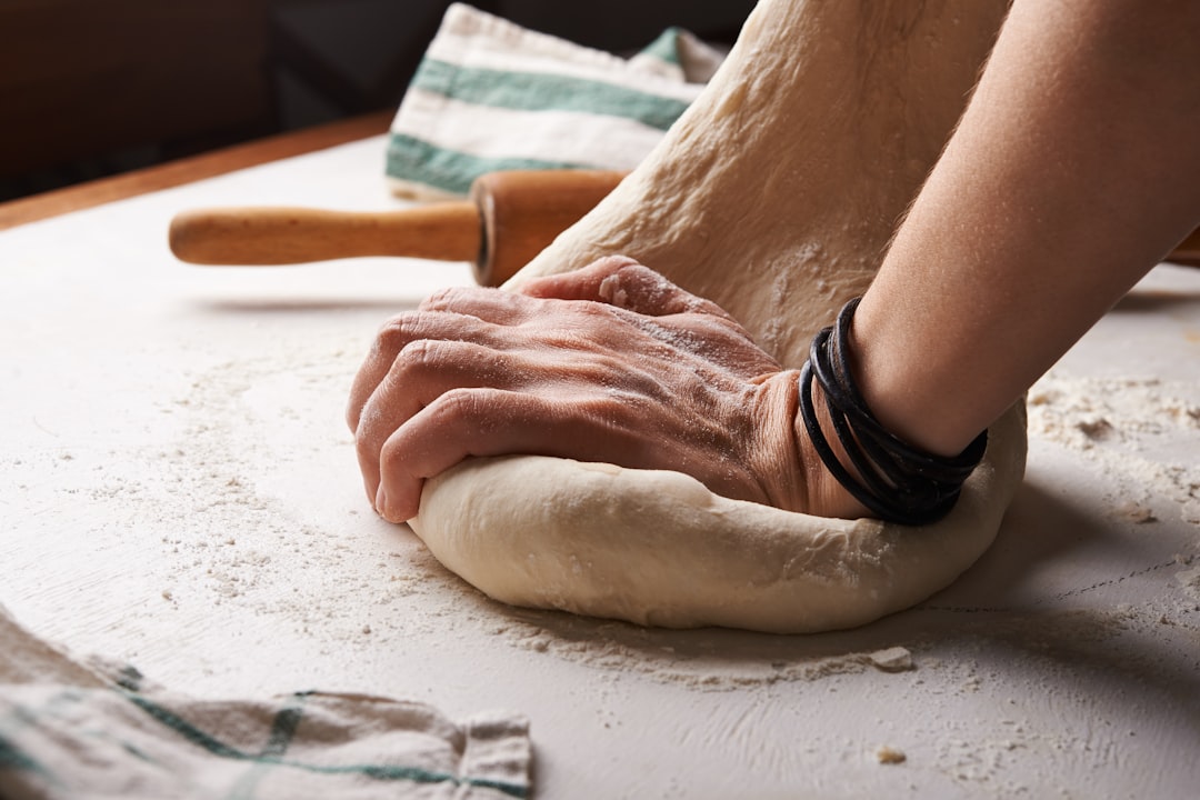 Les mains d'un boulanger pliant et laminant la pâte feuilletée avec précision